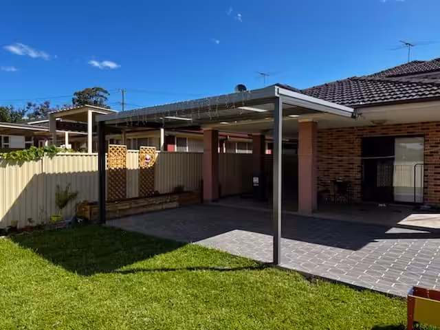 Sunny backyard with patio and lawn.