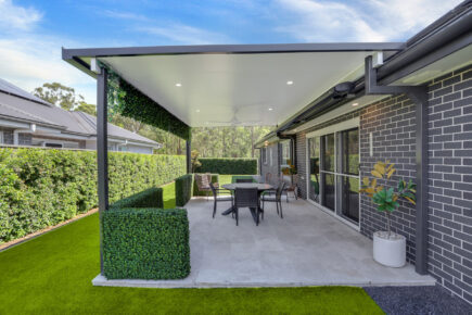 Modern outdoor patio with hedges and dining set.