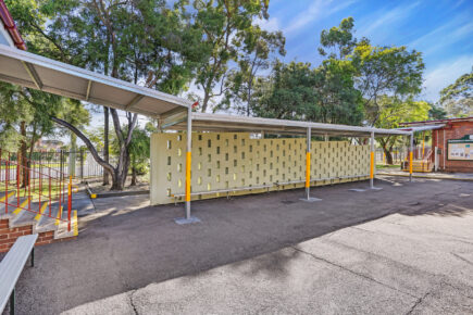 Covered outdoor area with perforated wall and trees.