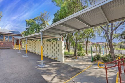 School walkway with metal roof and brick wall.