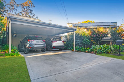 Two cars parked under a driveway awnings.