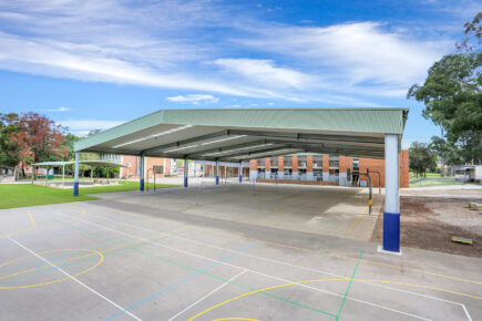 Outdoor basketball court with school cola structure.