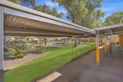 Covered walkway in school courtyard with green grass.