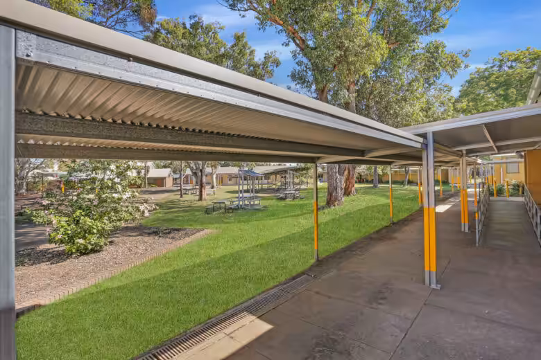Covered walkway in school courtyard with green grass.