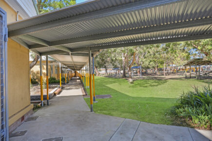 Covered walkway beside green schoolyard